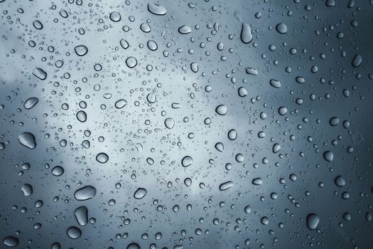 raindrops on glass with overcast sky background