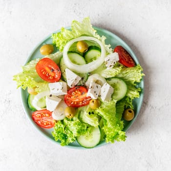 Healthy food. Top view of greek salad with olives and fresh vegetables on blue plate
