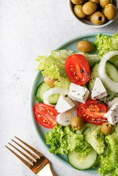 Healthy food. Top view of greek salad with olives, feta cheese and fresh vegetables on blue plate with golden fork