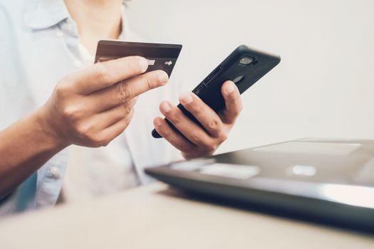 man looking at credit card and using smartphone for online shopping