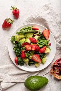 Healthy dieting. Fresh salad with strawberries, avocado and spinach top view flat lay on white background