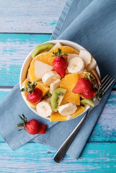 Healthy dieting. Fresh fruit salad on blue wooden background top view