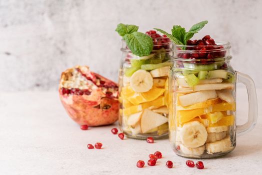 Healthy dieting. Fresh fruit salad with pomegranate in mason jars front view with copy space