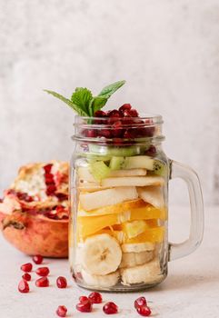 Healthy dieting. Fresh fruit salad with pomegranate in mason jar front view