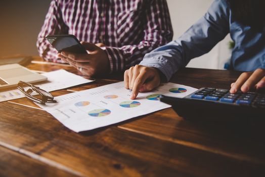 Businessman holding paperwork on the table and analyzing investment chart working in office. Business work concept. 