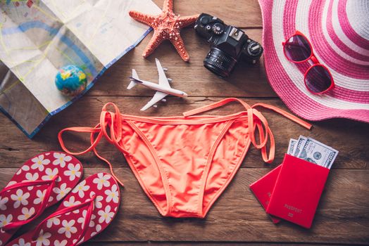 Beauty orange bikini and accessories on wooden floor for trip on summer 