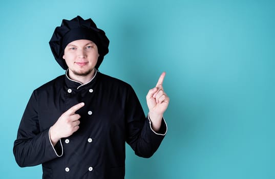 Young smiling male chef isolated on blue background with copy space