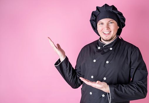 Young smiling male chef isolated on pink background with copy space