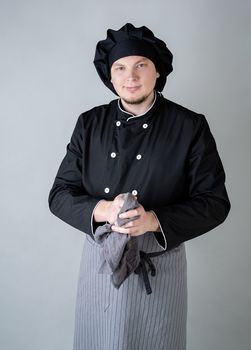 smiling male chef wipping his hands isolated on gray background