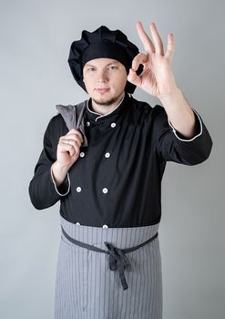 Young caucasian male chef showing ok sign isolated on gray background