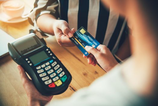 Close up of hand using credit card to pay by sending the credit card to the staff at the credit card swipe machine. Online payment