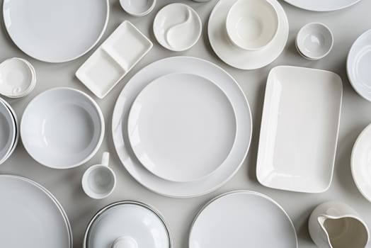 piles of white ceramic dishes and tableware top view flat lay on gray background