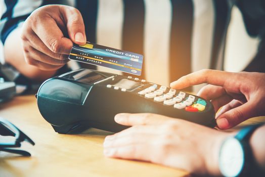 Close up of hand using credit card to pay by sending the credit card to the staff at the credit card swipe machine. Online payment