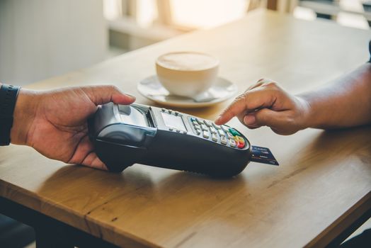 Close up of hand using credit card to pay by sending the credit card to the staff at the credit card swipe machine. Online payment