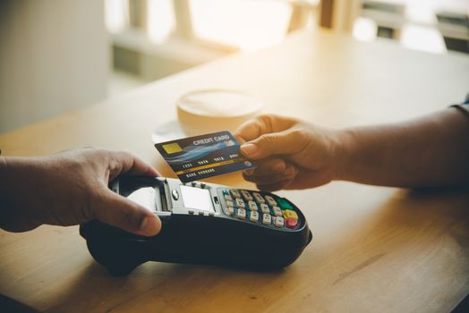 Close up of hand using credit card to pay by sending the credit card to the staff at the credit card swipe machine. Online payment