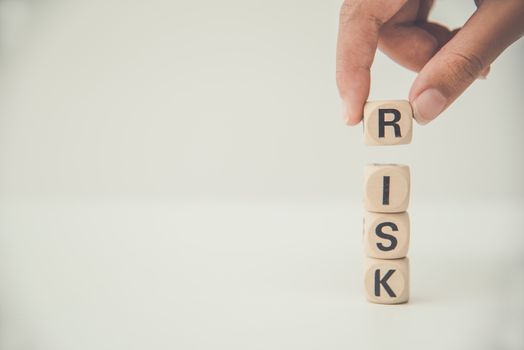 Hand hold wooden block with the word "RISK". Concept risk management