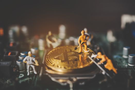 
Miniature people or small figure worker on  gold bitcoin.  Bit coin cryptocurrency banking money digital Bit Coin BTC Currency Technology Business Internet Concept.