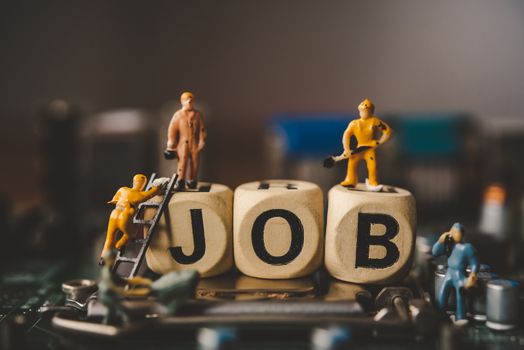 Miniature people or small figure worker on wood block with the word "job". Working for an organization concept.