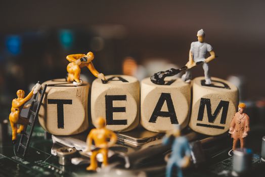 Miniature people or small figure worker on wood block with the word "TEAM". Teamwork for the organization concept.