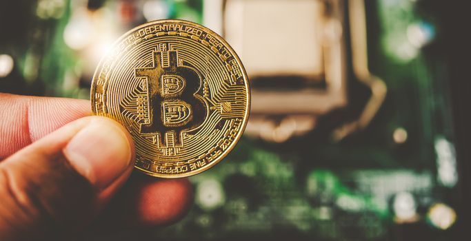 close-up hand of a businessman holding a gold bitcoin 