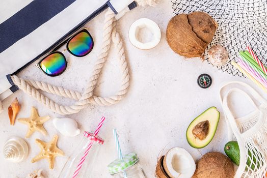 Vacation concept. Flat lay of mesh bags full of fruit, drinking glass, summer hat, sunglasses and starfish top view on white marble background with copy space