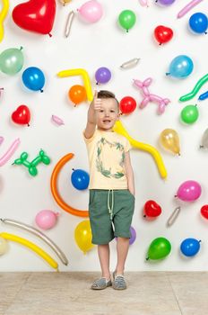 boy on a white background with colorful balloons. boy raising his hands up on a white background with balloons