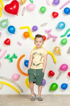 boy on a white background with colorful balloons. boy in a tank top and shorts on a white background with balloons in the shape of a heart