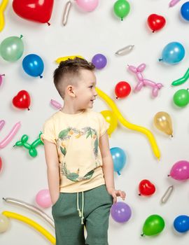 boy on a white background with colorful balloons. boy in a tank top and shorts on a white background with balloons in the shape of a heart