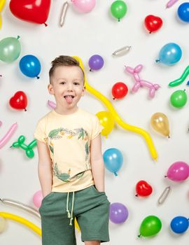 boy on a white background with colorful balloons. boy in a tank top and shorts on a white background with balloons in the shape of a heart