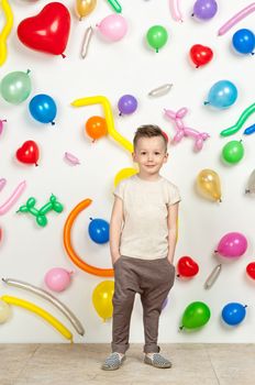 boy on a white background with colorful balloons. boy in a tank top and pants on a white background with balloons in the shape of a heart