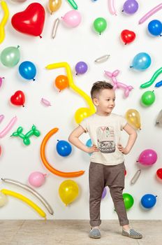 boy on a white background with colorful balloons. boy in a tank top and pants on a white background with balloons in the shape of a heart