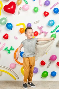 boy on a white background with colorful balloons. boy in a tank top and pants on a white background with balloons in the shape of a heart