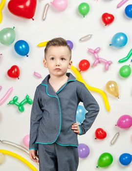 boy on a white background with colorful balloons. boy in pajamas on a white background with balloons in the shape of heart
