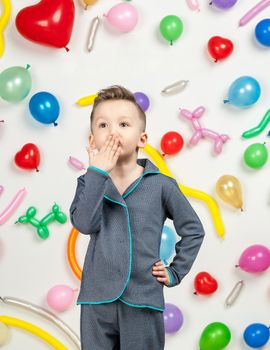 boy on a white background with colorful balloons. boy sending an air kiss on a white background with balloons in the shape of a heart