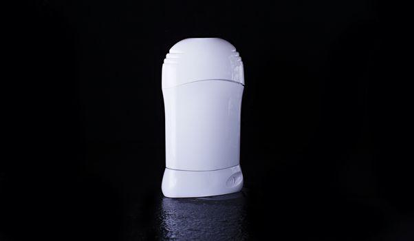 Dry deodorant in a white bottle on a black background with reflection below. Advertising photo of antiperspirant. Mock up deodorant.