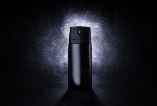 Deodorant in a black metal can on a black background with splashes at the back. Advertising photo of an aerosol antiperspirant. Mocap bottle with spray of water.