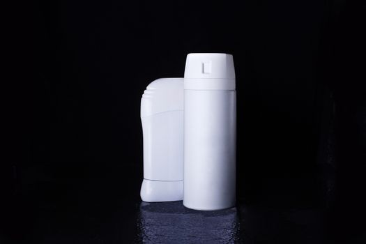 Dry and aerosol deodorant in a white bottle on a black background with reflection below. Advertising photo of antiperspirant. Mock up deodorant.
