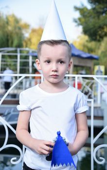 portrait of a sad little boy with a toy in his hand and the conical hat in the Park