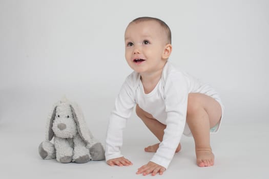 baby on a white background with a soft toy bunny