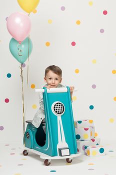 Boy in costume designer on a toy bike with balloons on a white background