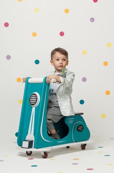 Boy in costume designer on a toy motorcycle on a white background