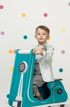 Boy in costume designer on a toy motorcycle on a white background