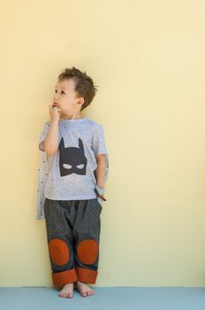 little boy in a suit with the image of Batman on a light yellow background