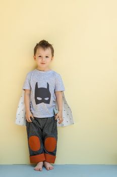 little boy in a suit with the image of Batman on a light yellow background
