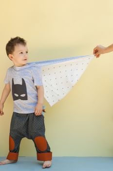 little boy in a suit with the image of Batman on a light yellow background