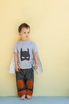 little boy in a suit with the image of Batman on a light yellow background