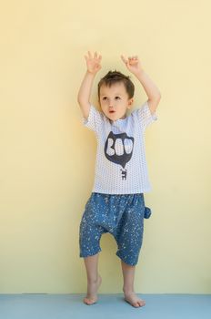 little boy in a shirt and shorts on a light yellow background