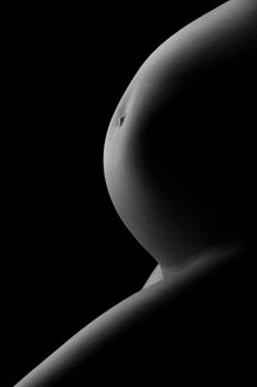 big belly of a pregnant woman on the side of a dark background