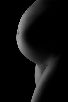 big belly of a pregnant woman on the side of a dark background