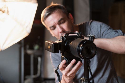 the young man adjusts the camera during photographing in the Studio